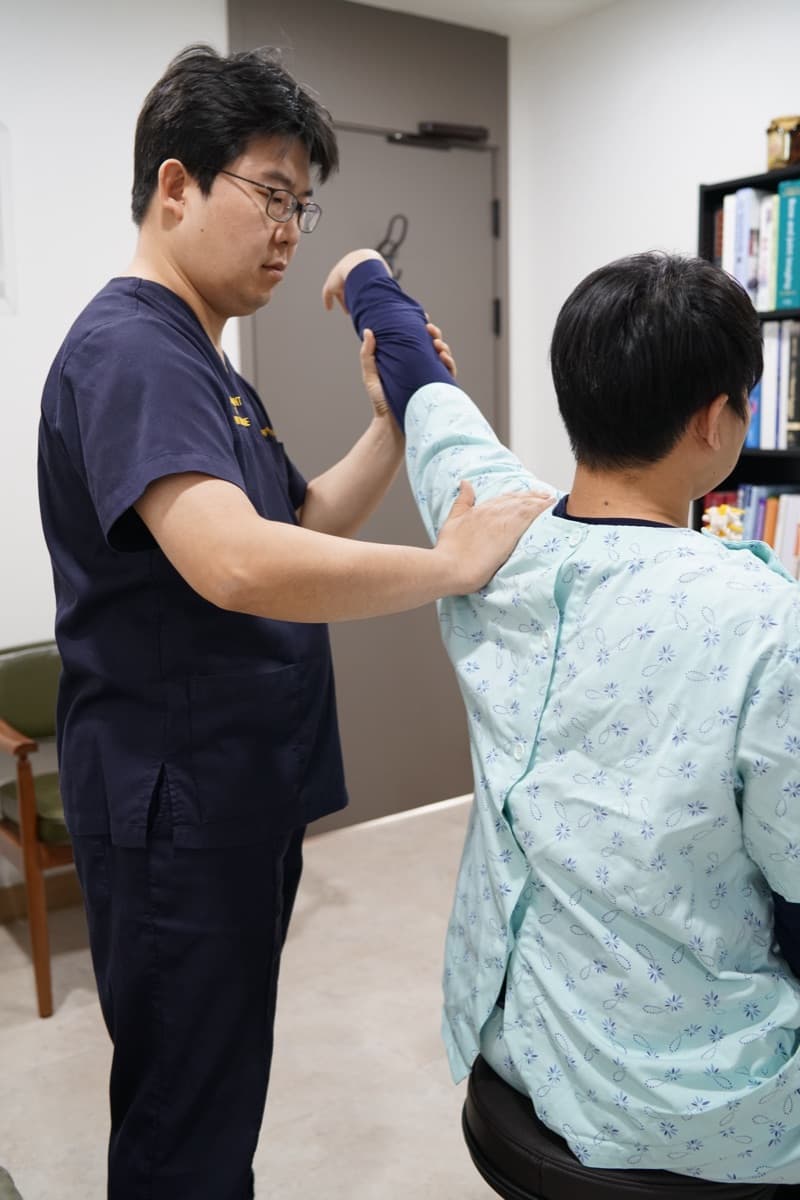 진료실에서 환자의 어깨 가동 범위를 확인하는 이학적 검사 모습